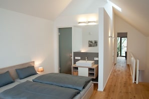 A modern bedroom with a large bed, a bedside table, a mirror, and a built-in sink. - urlaubsart - Schleibrücke (Kappeln)