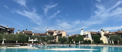 Una gran piscina con agua azul cristalina, rodeada de edificios con techos marrones y chimeneas blancas.