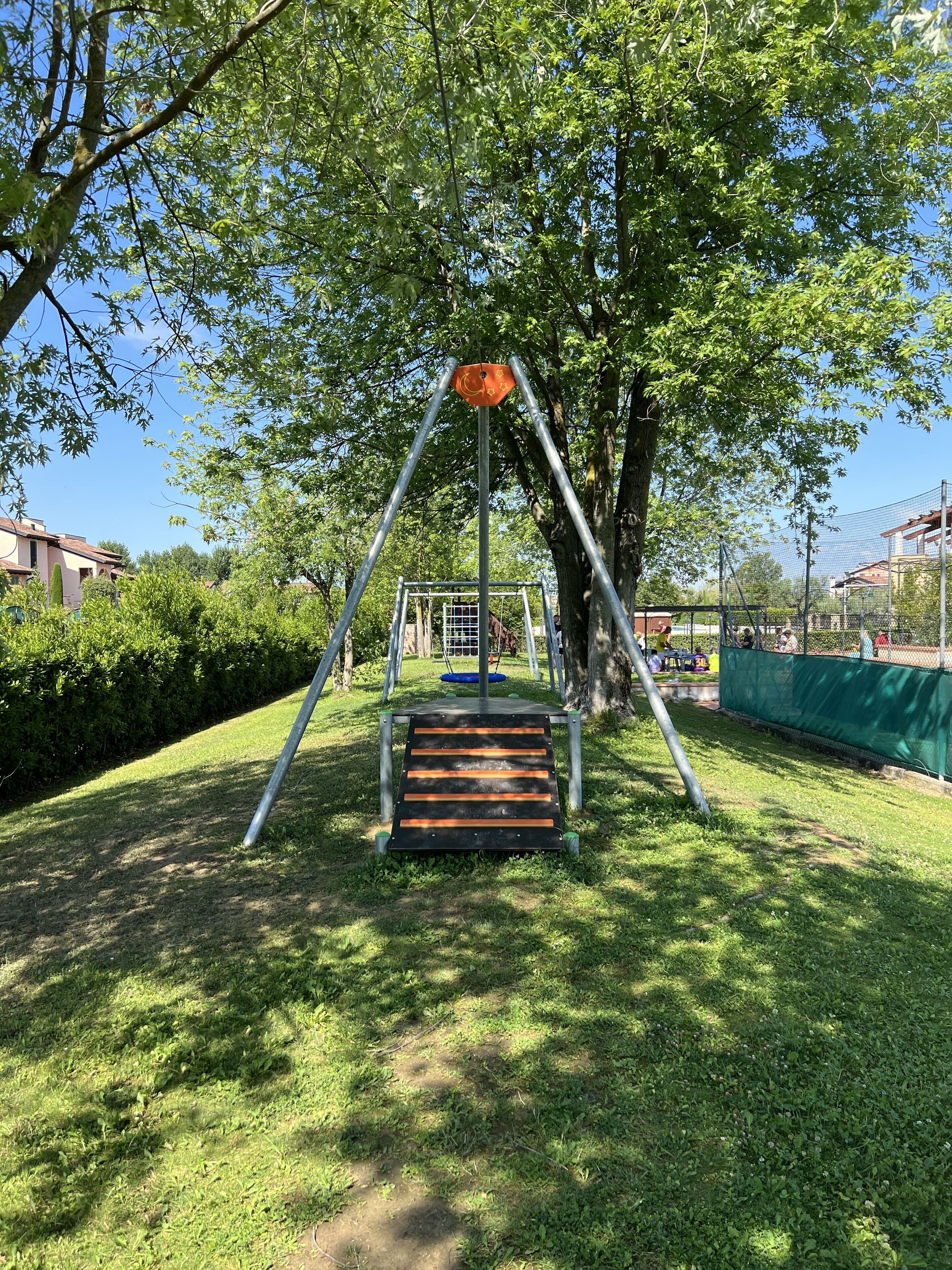 A playground with a swing set and a slide, surrounded by grass and trees.