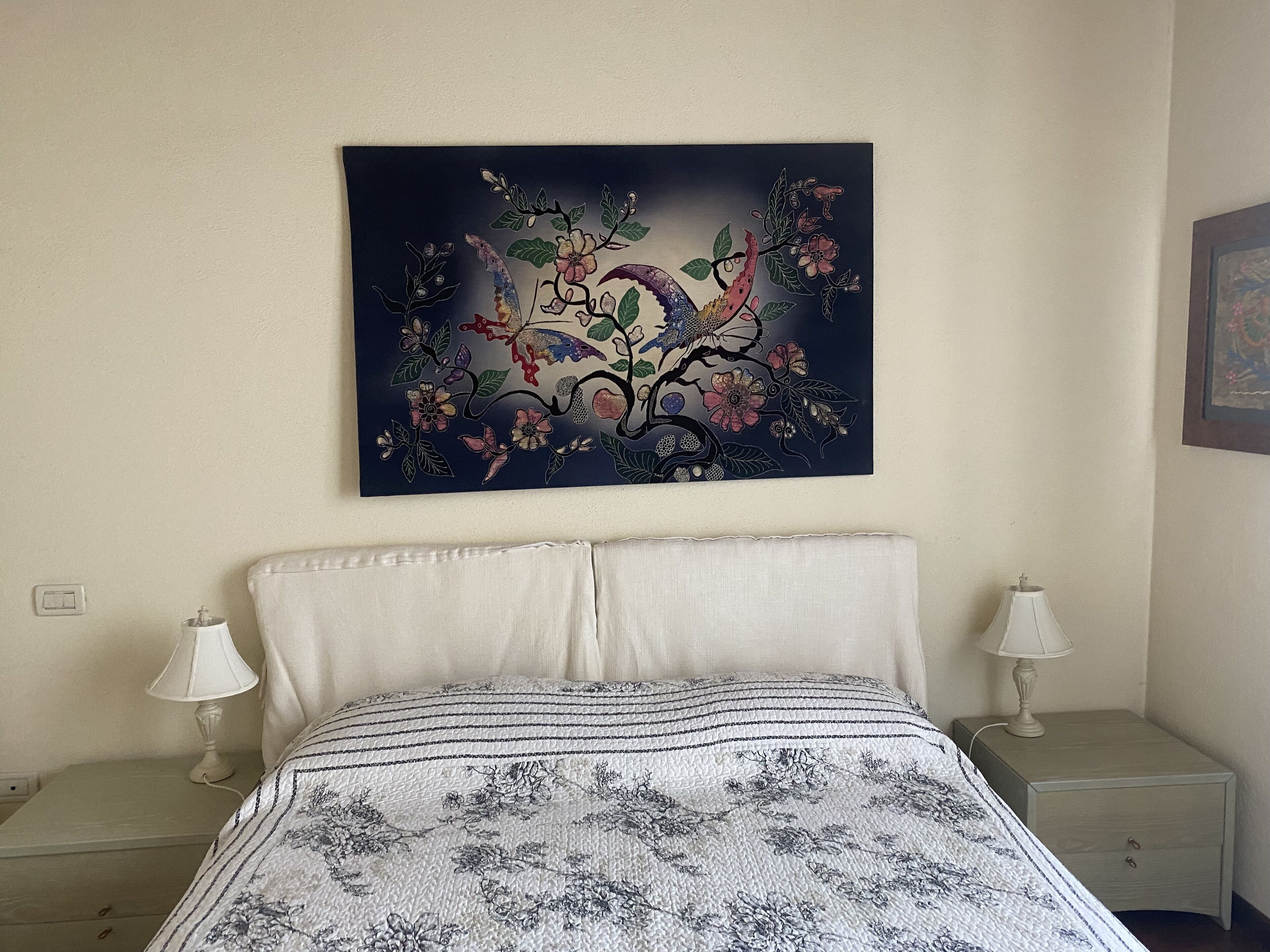 Un dormitorio con una cama, dos mesitas de noche y un cuadro colgado en la pared.