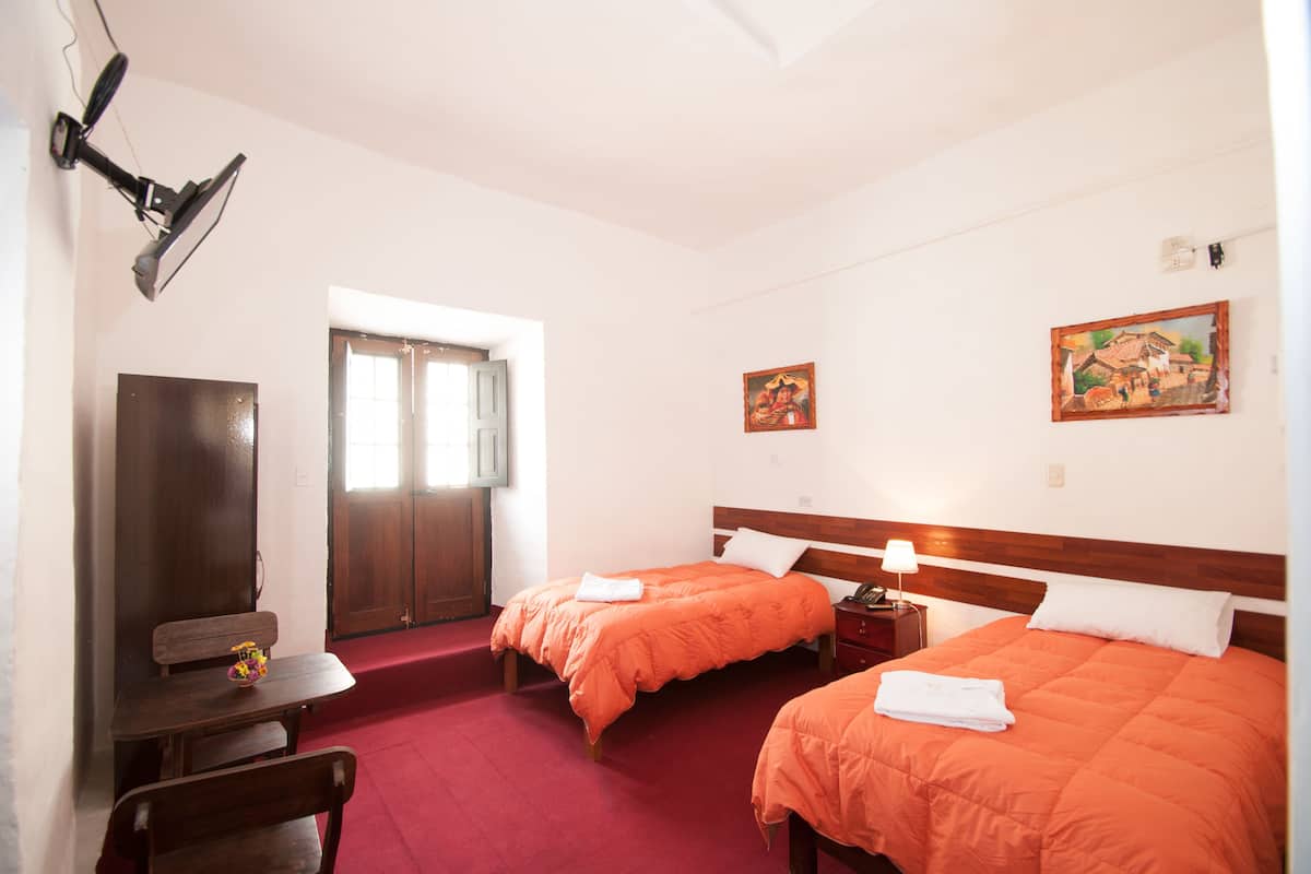 A hotel room with two beds, a desk, and a chair.