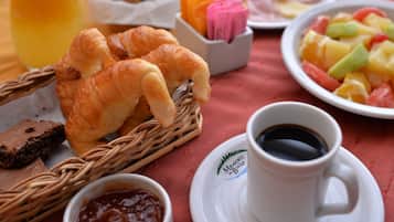 A breakfast setting with croissants, fruit salad, juice, and coffee.