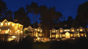 Un hotel de varios pisos con balcones iluminados y una entrada bien iluminada.