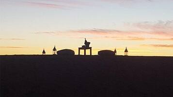A silhouette of a building with a central structure and smaller surrounding buildings against a sunset sky.