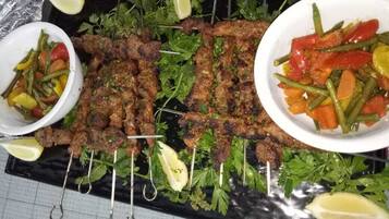 A tray of grilled meat skewers, a bowl of mixed vegetables, and a plate of grilled vegetables.