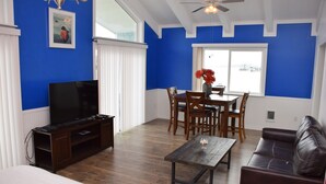 A living room with a TV, wooden furniture, and a dining area with a table and chairs. - Longliner Lodge and Suites (Sitka)