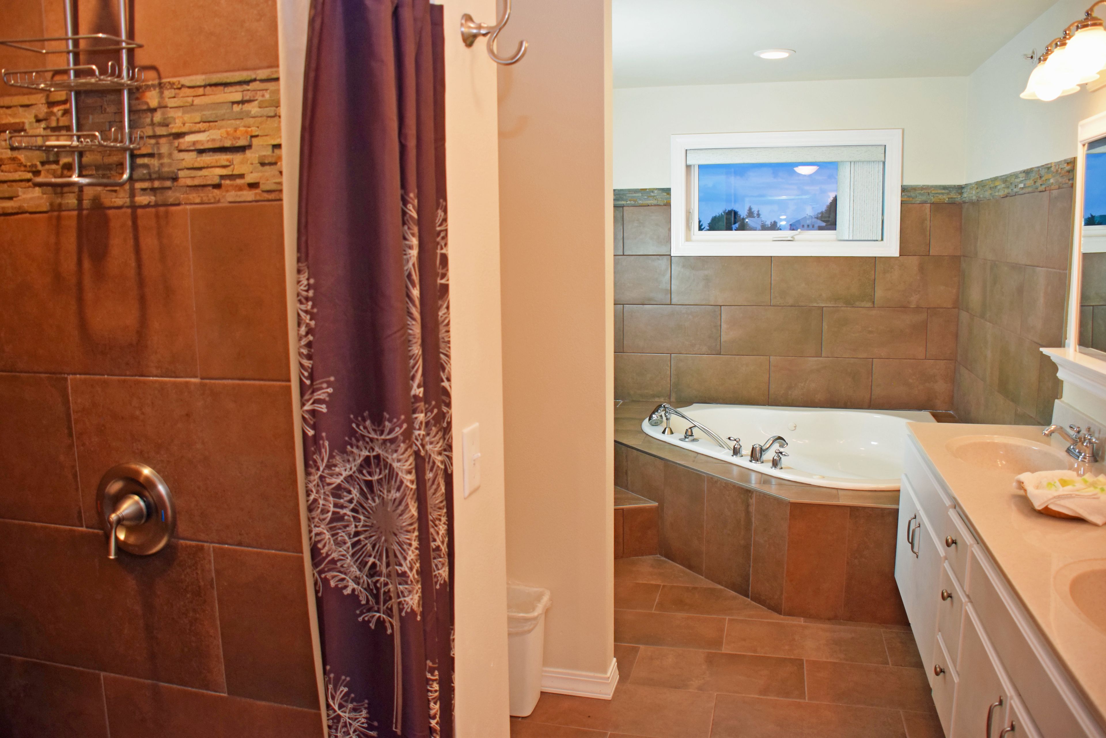 A bathroom with a bathtub, a shower area, and a vanity with a mirror.