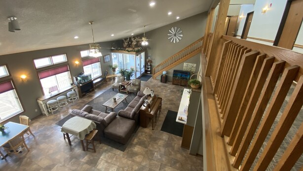A spacious living area with a high ceiling, a staircase, and a view of the outside. - SunRise Inn Hotel (Mondovi)