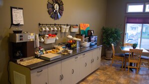 A breakfast bar with a coffee machine, mugs, and a clock on the wall. - SunRise Inn Hotel (Mondovi)