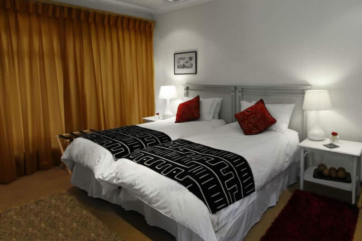 Ein Hotelzimmer mit einem großen Bett, zwei Nachttischen, einem roten Teppich und einem Deckenventilator.