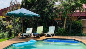 A swimming pool with lounge chairs and an umbrella. - No 5 on Franschoek Lane (Sandton)