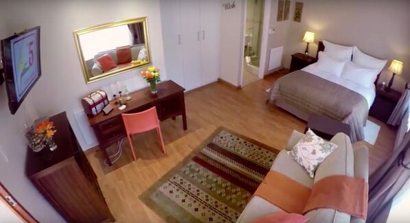A hotel room with a bed, a desk, a chair, a dresser, a mirror, and a window.