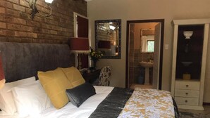A hotel room with a bed, a dresser, a mirror, and a bathroom visible through an open door. - No 5 on Franschoek Lane (Sandton)