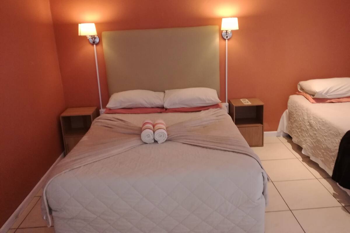 A hotel room with a large bed, two bedside tables, and two wall-mounted lamps.
