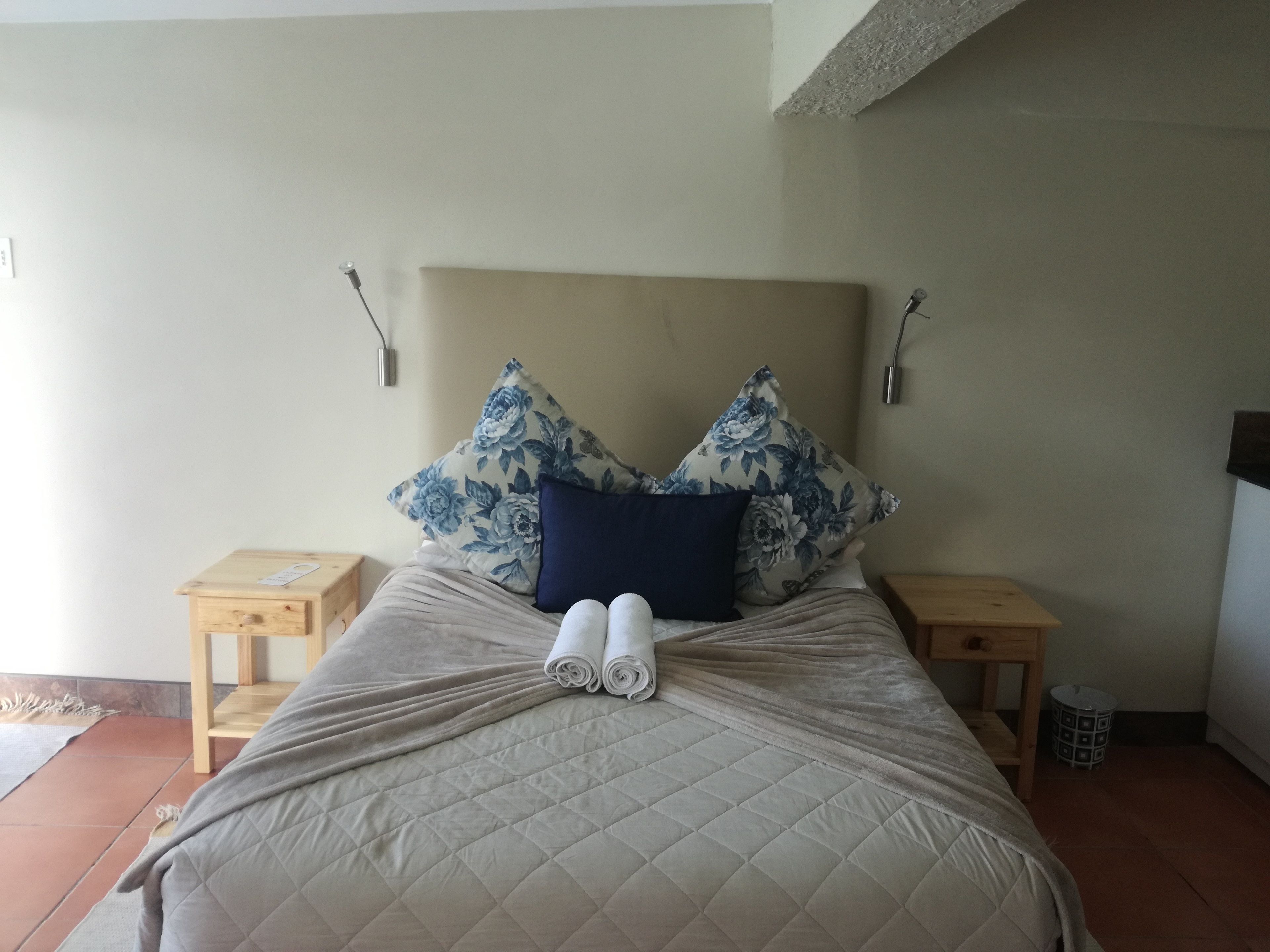 A neatly made bed with a quilted headboard, two nightstands, and floral-patterned pillows.