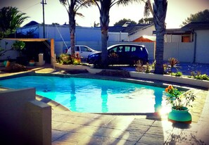 Relax by the rectangular pool surrounded by lush greenery and palm trees.