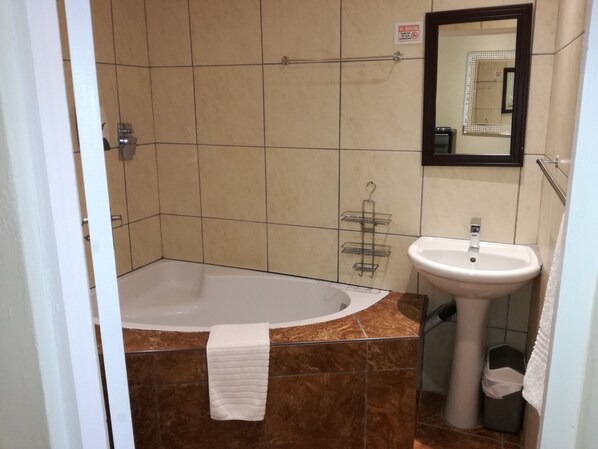 A bathroom with a bathtub, a sink, and a mirror.