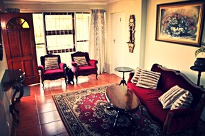 Classic living room with a red sofa, wooden coffee table, and armchairs, set against a warm and inviting atmosphere.