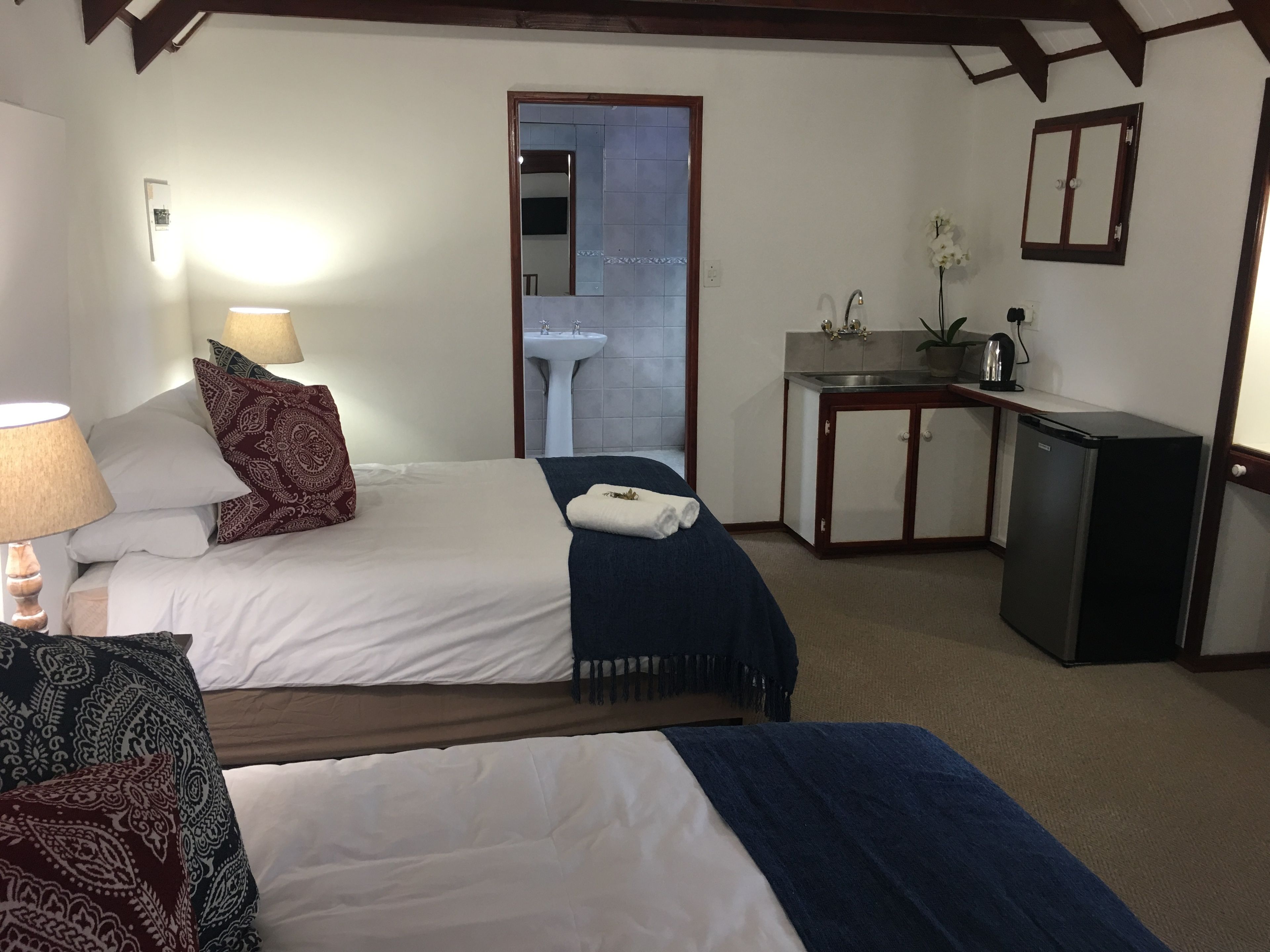 Een hotelkamer met twee bedden, een bureau, een wastafel en een koelkast.