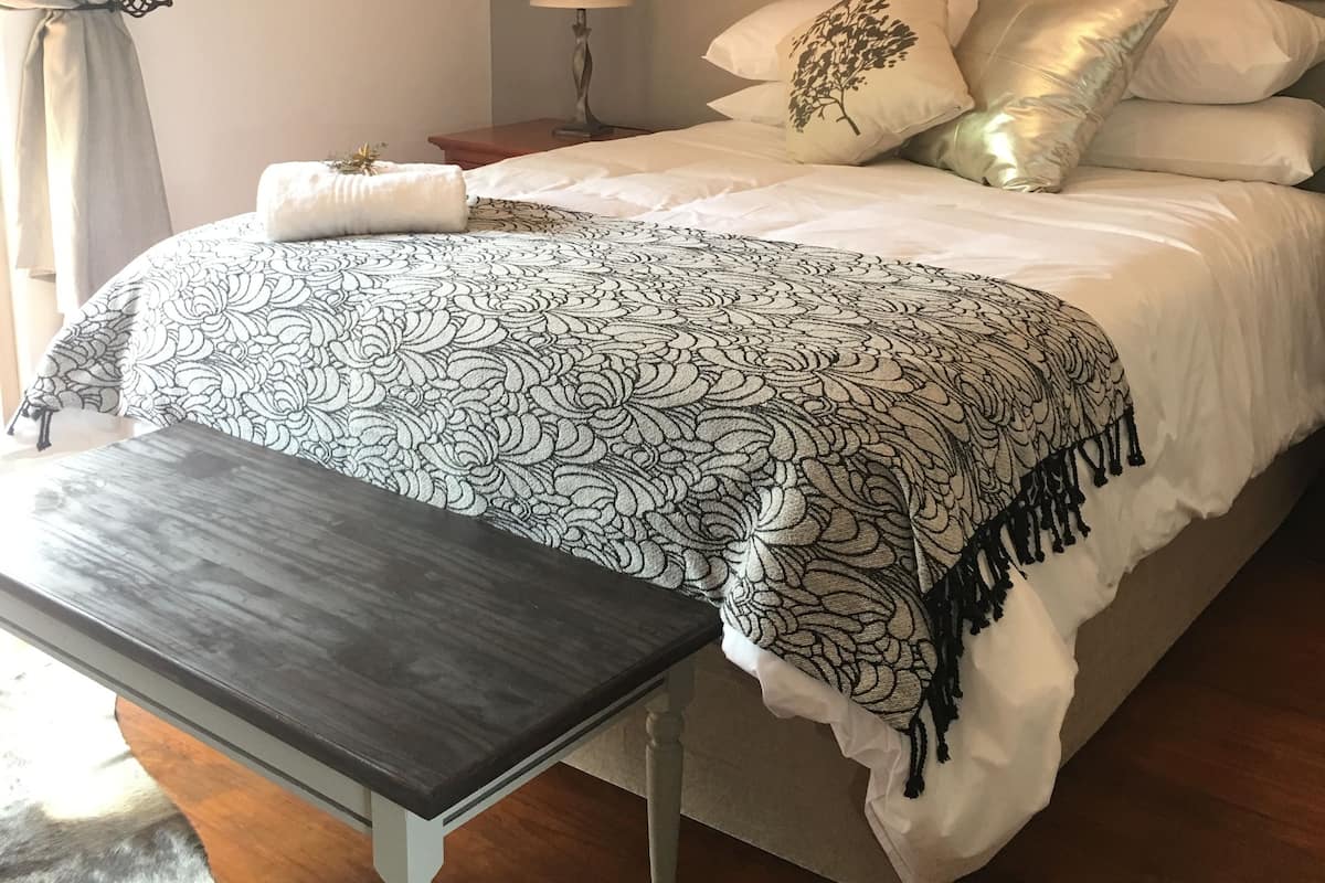 Une chambre à coucher avec un lit, une table de chevet, une lampe et un tableau encadré au mur.