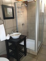 Um banheiro com pia branca, espelho, porta-toalhas, chuveiro e banheira.