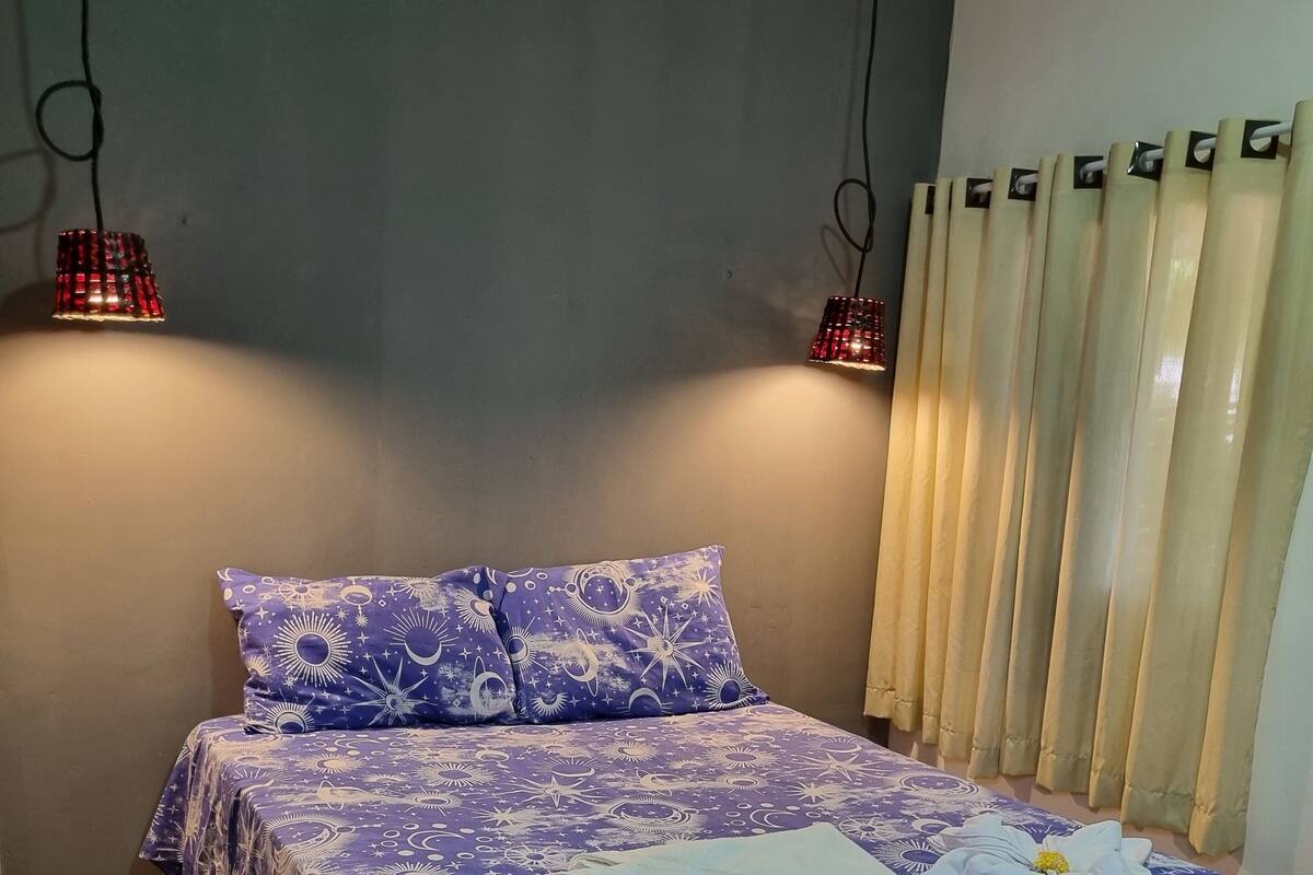 Een bed met een blauw-witte sterrenspreidek, twee kussens en een opgevouwen handdoek op het bed.