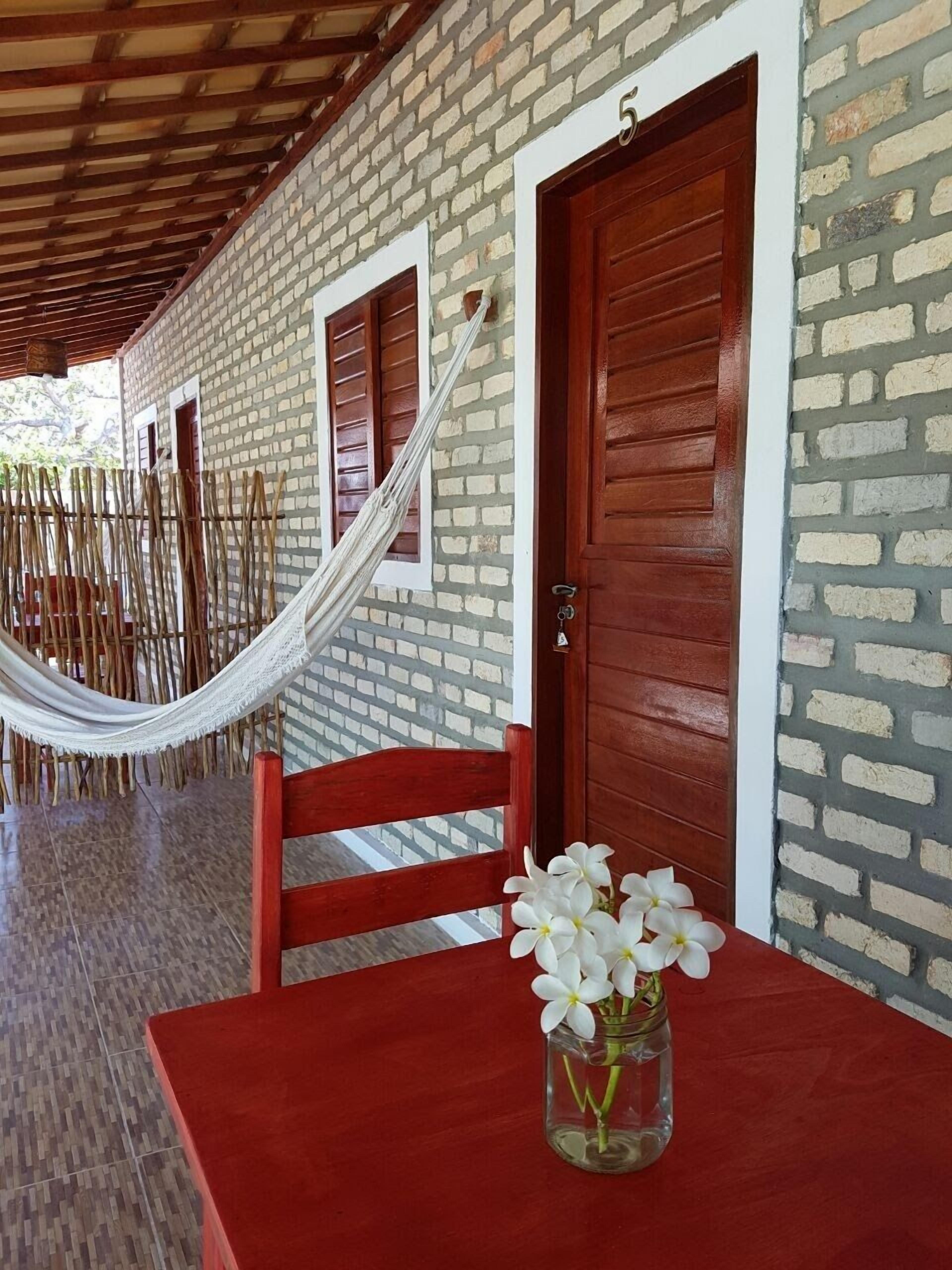 A room with a red table, a wooden chair, a hammock, and a door with the number 5.