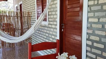 A room with a red table, a wooden chair, a hammock, and a door with the number 5.
