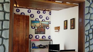 Una habitación con un escritorio de madera, estanterías con carpetas y cuadros en la pared.