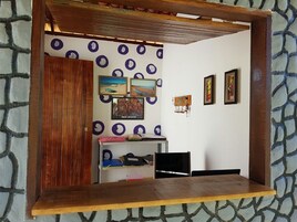 Um quarto com escrivaninha de madeira, estantes com fichários e quadros nas paredes.