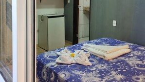 Una habitación con una cama, un escritorio pequeño, un televisor y una puerta que da a otra habitación.
