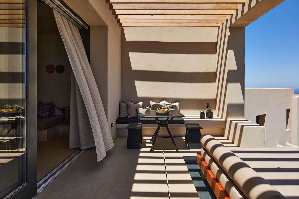 A modern outdoor seating area with a table and chairs, a sofa, and a small table with a bowl of fruit.