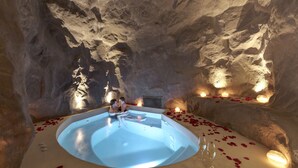 An indoor pool with a circular shape, surrounded by stone walls and candles. - North Santorini - A Luxury Spa Hotel (Santorini)