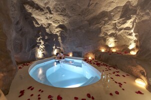 Una piscina interior de forma circular, rodeada de muros de piedra y velas.