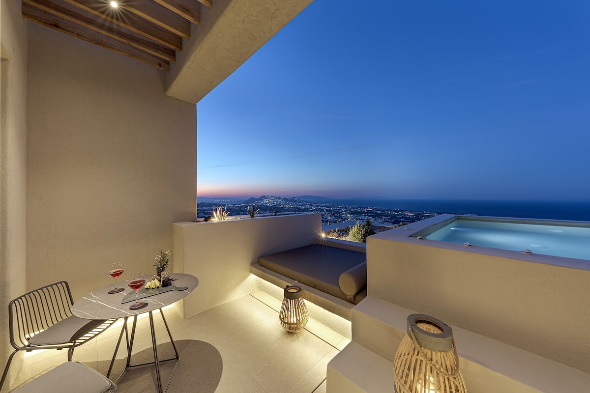 A modern outdoor seating area with a table, chairs, and a small table lamp.