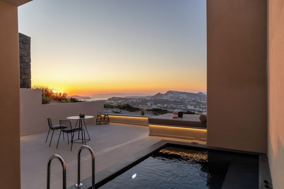 A rooftop terrace with a pool, seating area, and a view of the sunset over a cityscape.