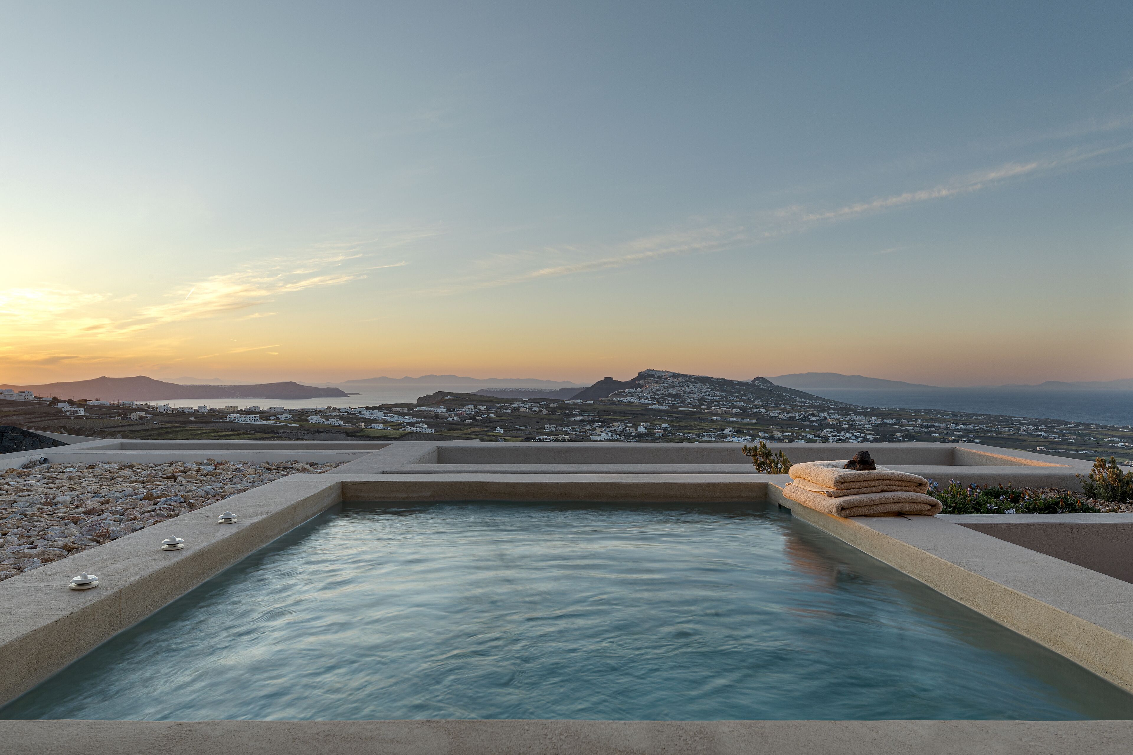 A pool with a view of a coastal landscape and distant mountains.