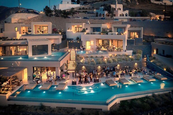 Un resort moderno con una amplia piscina al aire libre, varias zonas de restauración y vistas a la colina.