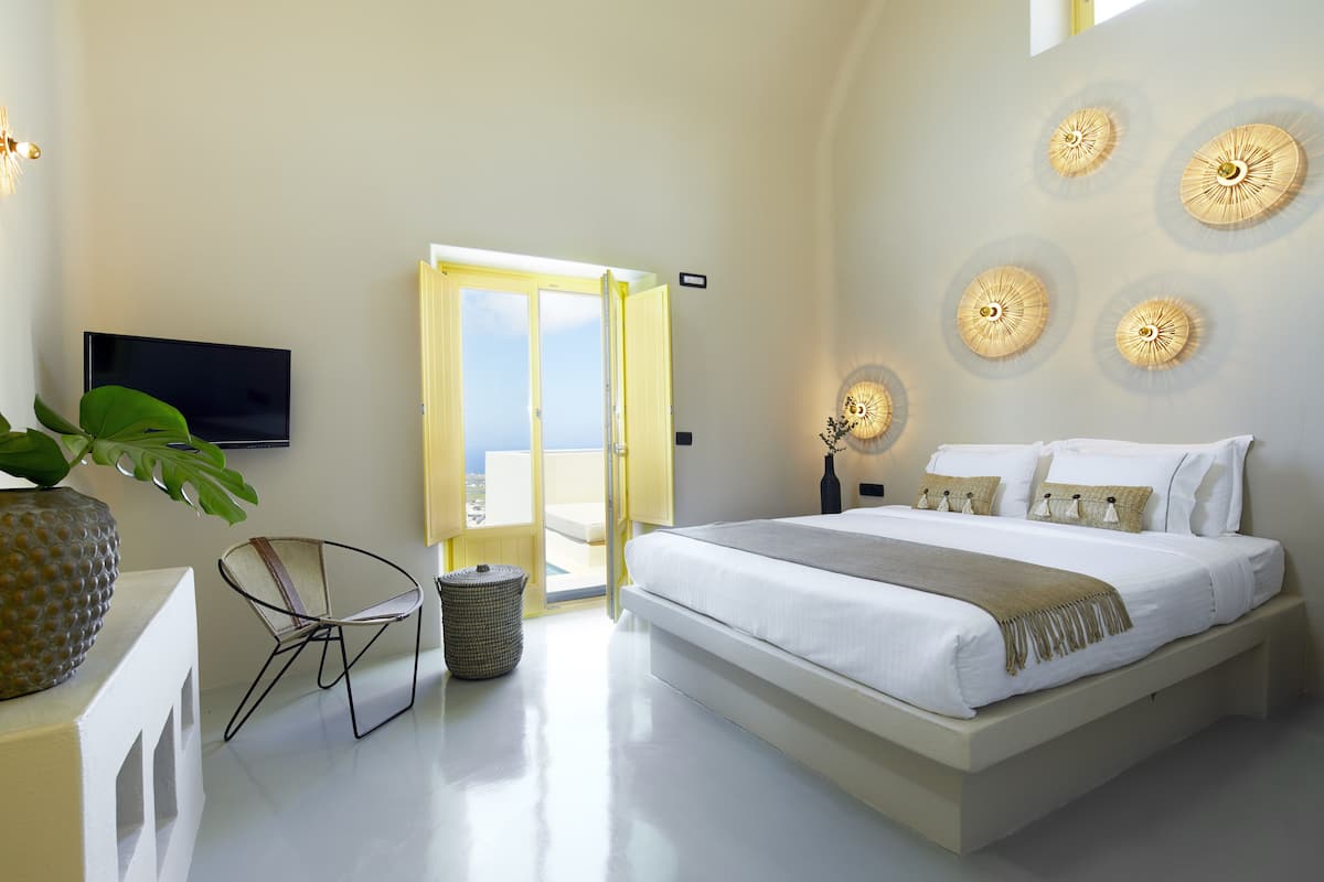 A modern bedroom with a large bed, a TV mounted on the wall, and a balcony door.