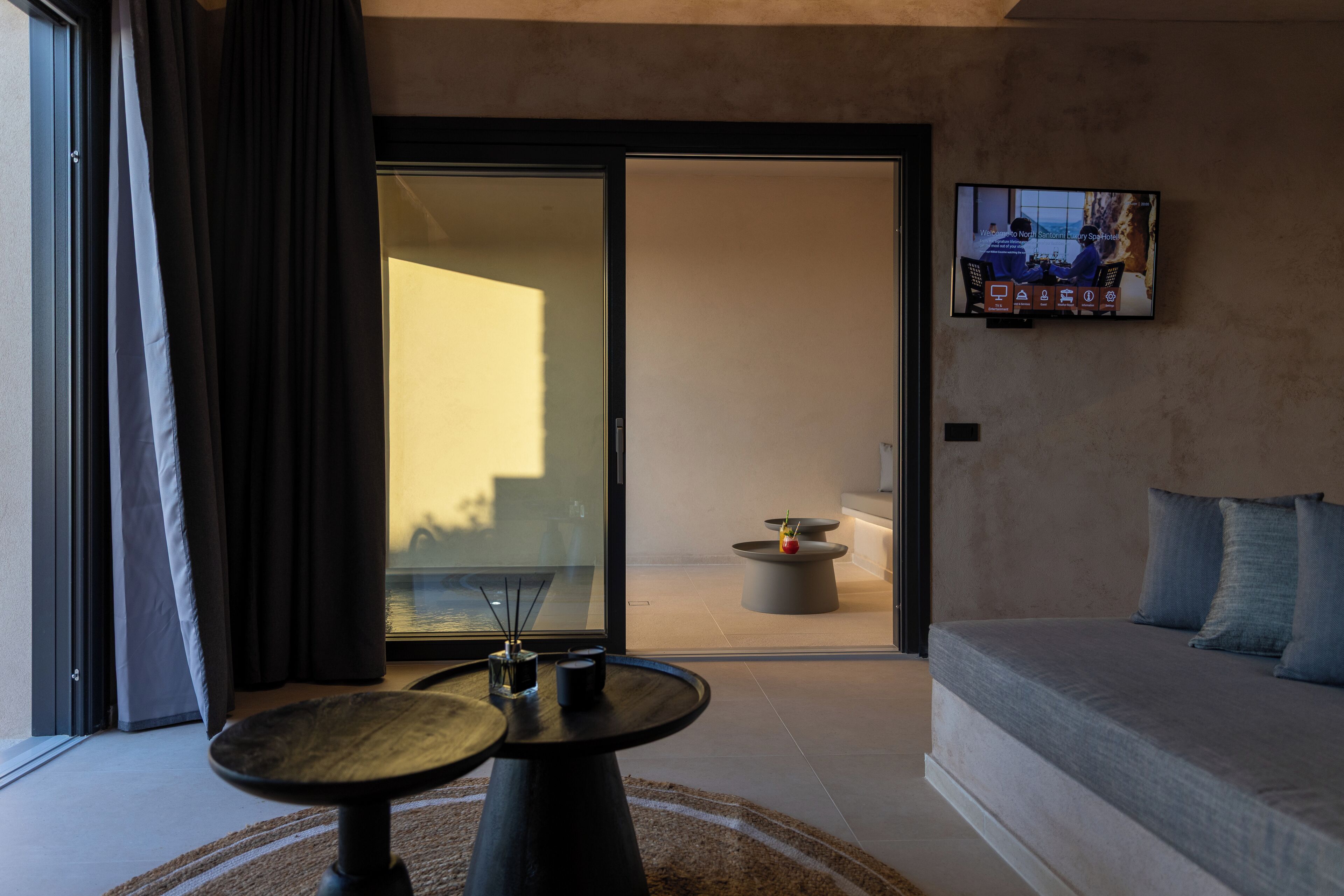 Een moderne woonkamer met een bank, een salontafel en een aan de muur bevestigde televisie.