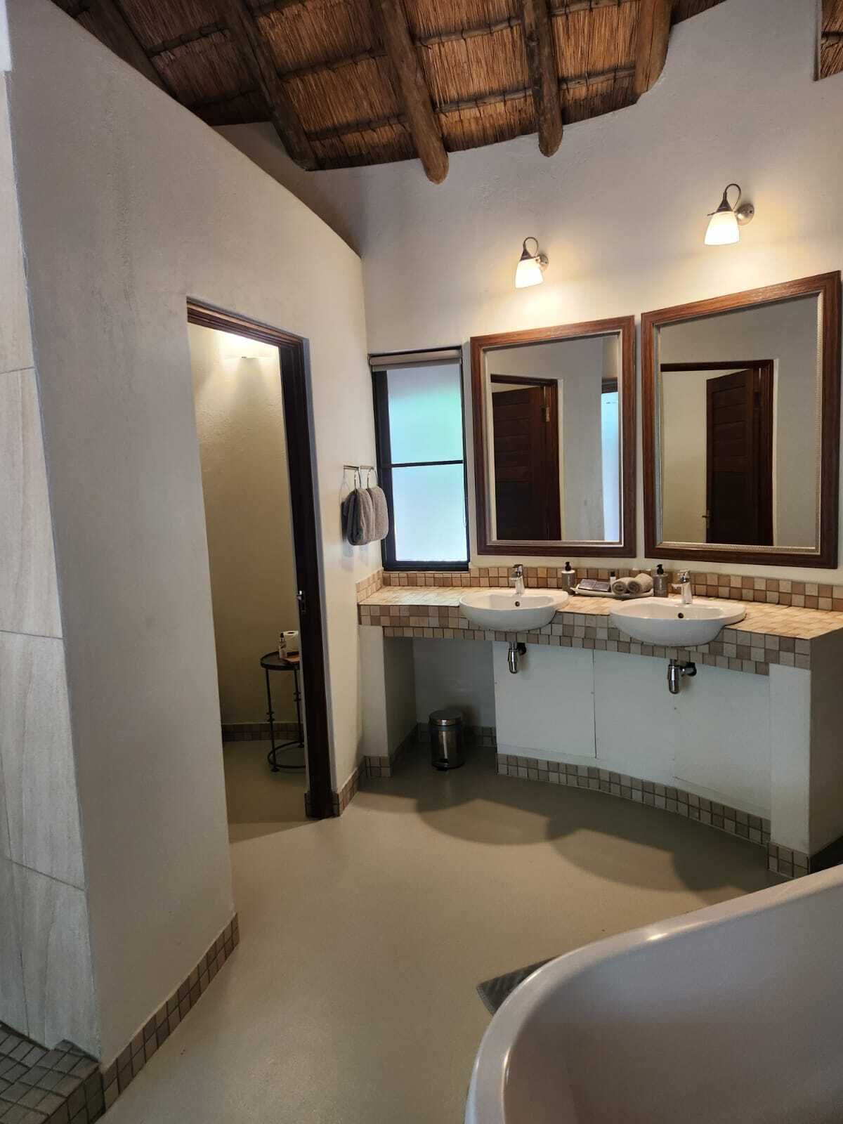 Une salle de bain avec deux lavabos, un grand miroir et une baignoire.