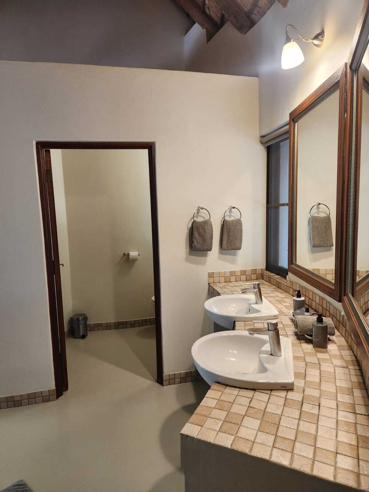 Une salle de bain avec deux lavabos, un grand miroir et un sol carrelé.