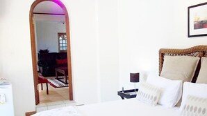 A hotel room with a bed, a nightstand, a lamp, and a mirror. - Mizizi House of Sandton Bed & Breakfast (Sandton)