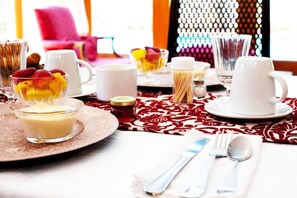 A breakfast setting with a table set for two, including plates, bowls, cups, and utensils. - Mizizi House of Sandton Bed & Breakfast (Sandton)