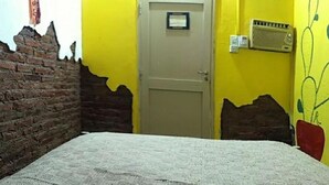 A room with a bed, a door, a brick wall, and a radiator.