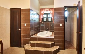 A bathroom with a freestanding bathtub, a vanity with a mirror, and a door leading to another room.