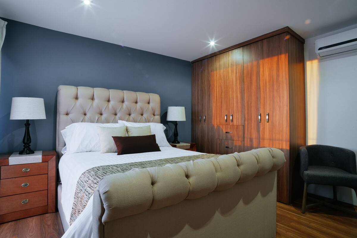 Un dormitorio con una cama grande, un armario de madera y una silla.