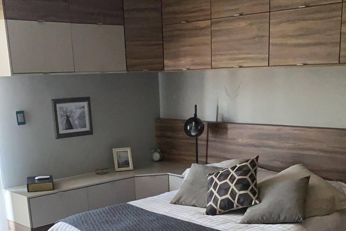 Un dormitorio moderno con una cama grande, una mesita de noche y una lámpara de pared.