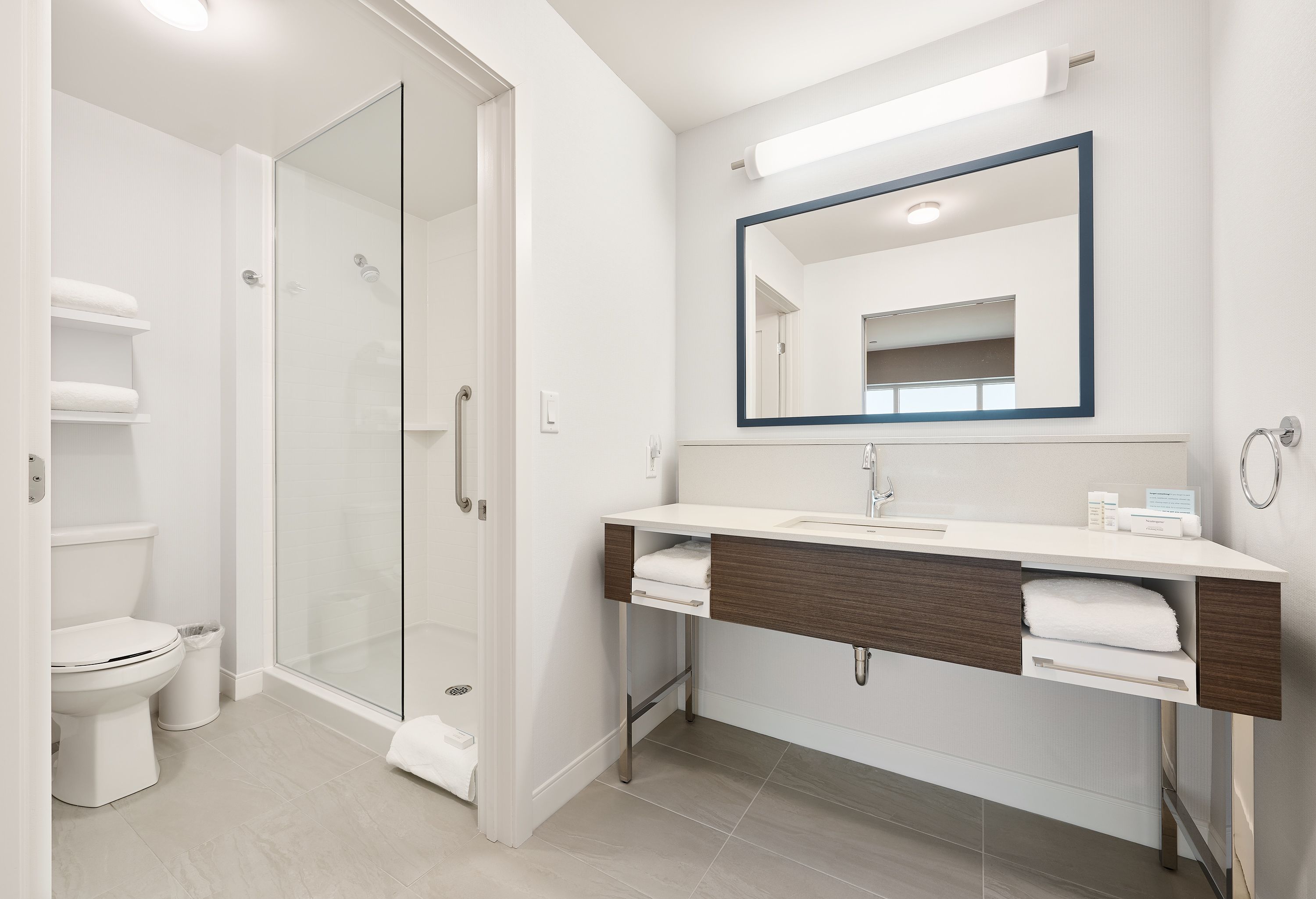 Un baño moderno con cabina de ducha de vidrio, inodoro blanco y tocador con espejo.