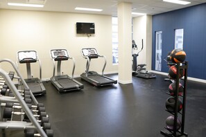 Et fitnesscenter med løbebånd, håndvægte og et rack til medicinbolde.